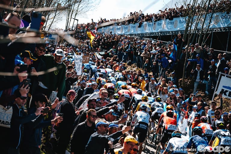 Riders ascend the Oude Kwaremont at the 2025 Tour of Flanders, bordered by massive throngs of fans on both sides.